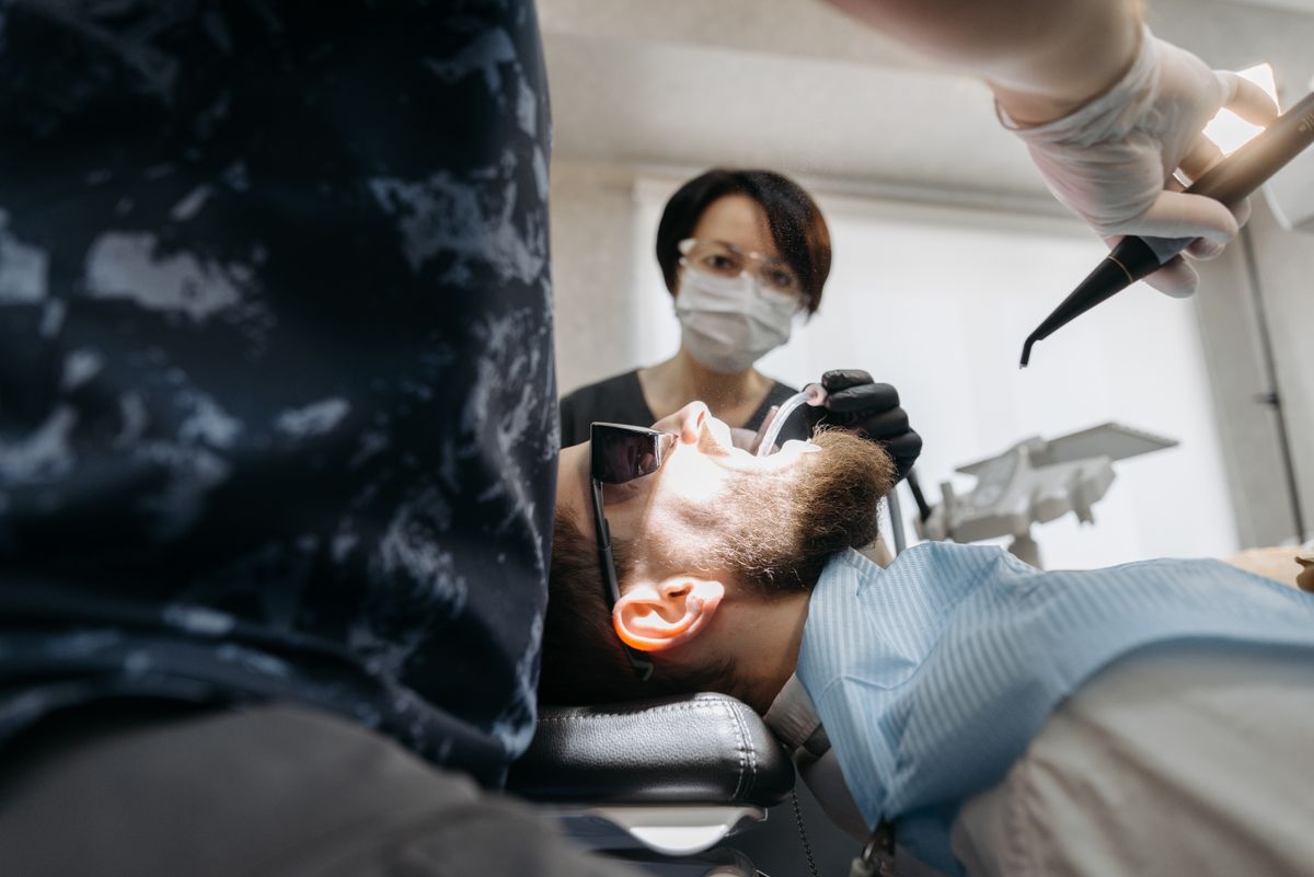 Un dentista examina la boca de un paciente en el sillón dental.